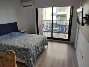 a bedroom with a bed and a balcony with chairs at Monoambiente céntrico a estrenar in Rosario