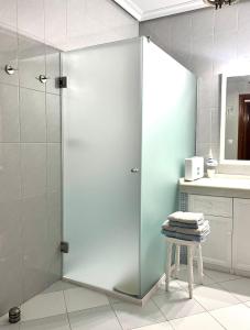una puerta de ducha de cristal en un baño con taburete en Apartamento Turístico Casa Bari, en Olivenza