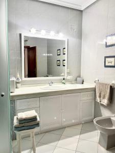 Baño blanco con lavabo y espejo en Apartamento Turístico Casa Bari, en Olivenza