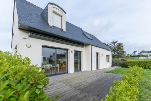 a white house with a wooden deck at TY KREIZH - Maison neuve avec piscine proche mer in Saint-Pabu