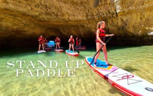 a woman standing on a stand up paddle board in the water at Lovely 3BD 150m Beach Ocean View AC Wi-Fi Balcony in Albufeira