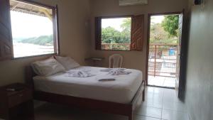 Dormitorio con cama y vistas al agua en BELAS PRAIAS POUSADA en Alter do Chao
