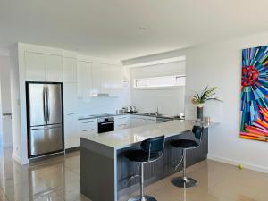 a kitchen with a refrigerator and two bar stools at Sea Retreat - Esplanade Available Xmas 2023 and 2024 Summer in Robe