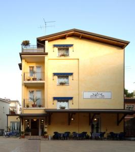 un bâtiment avec des tables et des chaises devant lui dans l'établissement Hotel Lido, à Lido di Jesolo