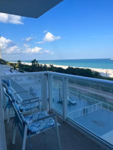 einen Stuhl auf einem Balkon mit Blick auf den Strand in der Unterkunft Pavilion Beach Front Apartment with Balcony in Miami Beach