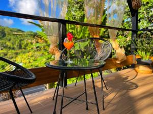 a glass table with a drink on a balcony at Cocon des jardins - Bungalow & SPA in Gros-Morne