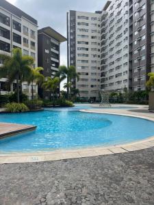 a large swimming pool with palm trees and buildings at Zen Living Condo at Avida Atria Tower 2 in Iloilo City