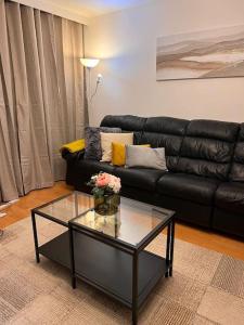 a living room with a black leather couch and a glass table at Stunning 2 Bedroom duplex in the Heart of London in London