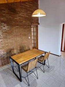 uma mesa de madeira e cadeiras num quarto com uma parede de tijolos em La Primi em Guaymallén