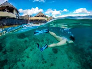 a woman swimming in the water in front of a resort at Koro Sun Resort & Rainforest Spa in Savusavu