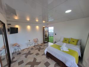 1 dormitorio con 1 cama, TV y sillas en Hostal Gosén en Puerto Baquerizo Moreno