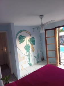 un dormitorio con una pared con una pintura de palmeras en Da Lua Hostel, en Ubatuba