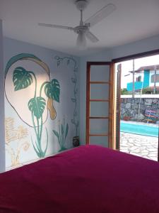 Dormitorio con cama morada y pintura en la pared en Da Lua Hostel en Ubatuba