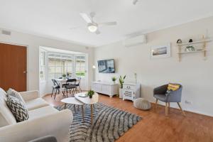 a living room with a couch and a table at Belle Escapes - Vitamin Sea at Henley Beach in Henley Beach