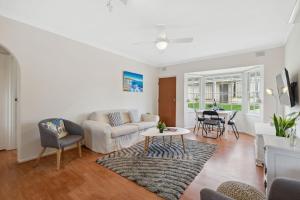 a living room with a couch and a table at Belle Escapes - Vitamin Sea at Henley Beach in Henley Beach