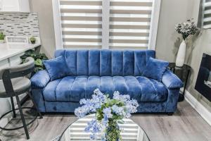 un sofá azul en una sala de estar con un jarrón de flores en Hugh's and Nora's Place to stay, en Brooklyn