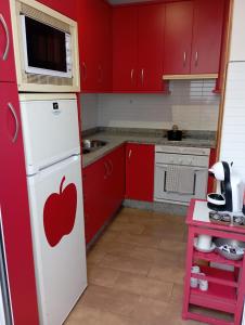 a kitchen with red cabinets and an apple on the refrigerator at Apartamento Duquesa in Rute