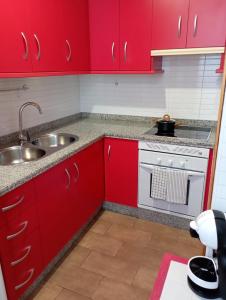 cocina roja con fregadero y fogones en Apartamento Duquesa en Rute