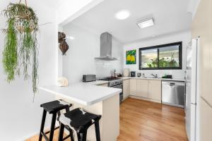a kitchen with a white counter and stools at Villa Del Mar - Belle Escapes Jervis Bay in Vincentia