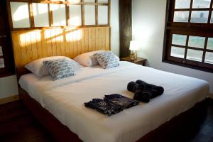 - une chambre avec un grand lit blanc et des serviettes dans l'établissement บ้านฮิดะ หางดง, à Ban Phae Khwang