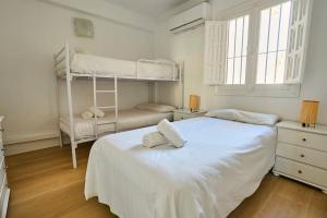 a white bedroom with two bunk beds in it at Front Sea Line Experience in Fuengirola