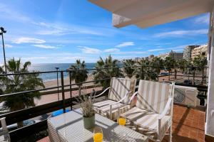 een balkon met een tafel en stoelen en het strand bij Front Sea Line Experience in Fuengirola