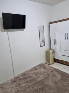 een woonkamer met een tv aan de muur en een kussen bij Studio Ideal in Sao Paulo