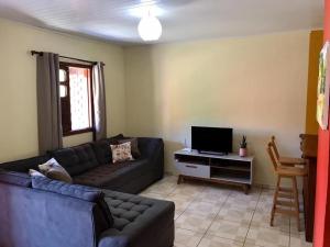a living room with a couch and a television at Casa Rosa in Vale do Capao