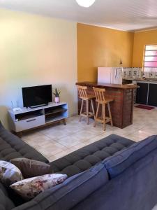 a living room with a couch and a kitchen at Casa Rosa in Vale do Capao