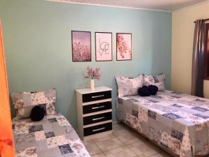 a bedroom with two beds and a dresser at Casa Rosa in Vale do Capao