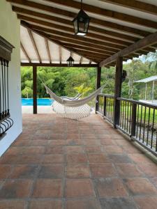a hammock on a covered patio with a pool at Finca ganadera de lujo en el Quindío in Pueblo Tapao
