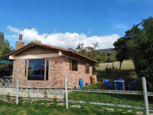 a small brick house with blue chairs in front of it at Rancho New Life Guatavita in Guatavita
