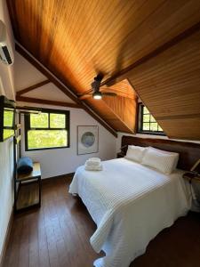 a bedroom with a large white bed with wooden ceilings at Pousada Motta in Miguel Pereira