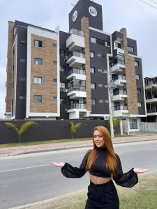 uma mulher de pé ao lado de uma rua com um edifício em Cobertura Duplex Itapoá em Itapoá