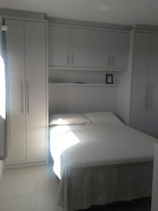 um quarto branco com uma cama e armários brancos em Cobertura Duplex Itapoá em Itapoá