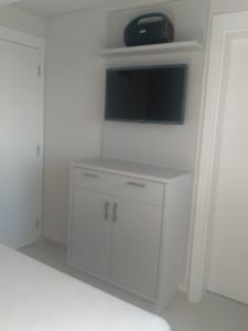 uma sala de estar com televisão e armários brancos em Cobertura Duplex Itapoá em Itapoá