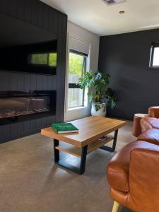 'Shore Thing' - Akaroa في سانت هيلينز: غرفة معيشة مع طاولة قهوة وأريكة