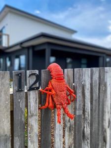 a red stuffed animal sitting on top of a fence at 'Shore Thing' - Akaroa in St Helens