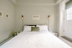 a large white bed in a white room with a window at Airy Greenwich Retreat with Private Deck in New York