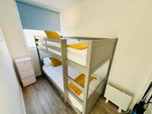 a bunk bed in a small room with a window at 2 Bedroom Chalet SB22, Sandown Bay, Isle of Wight, Dog Friendly in Sandown