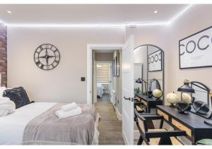 a bedroom with a bed and a desk and a clock at Modern London 3-Bedroom Flat in London