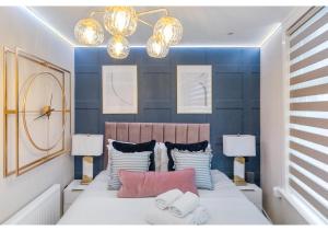 una camera da letto con un letto con pareti blu e due luci di Modern London 3-Bedroom Flat a Londra