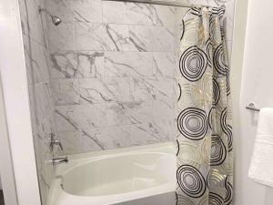 a bathroom with a white tub and a shower curtain at Modern 1br - 15 from Airport in Stockbridge