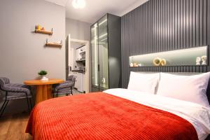 TAKS-INN Suites في إسطنبول: غرفة نوم بسرير وبطانية حمراء وطاولة
