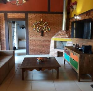 uma sala de estar com uma mesa e uma lareira de tijolos em Sossego entre as montanhas de Itaipava em Petrópolis