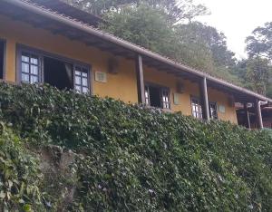 una casa amarilla con un seto delante de ella en Sossego entre as montanhas de Itaipava, en Petrópolis