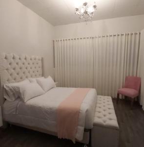 1 dormitorio con cama blanca y silla rosa en Hotel Casablanca, en Ollantaytambo