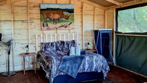 ein Schlafzimmer mit einem Bett in einer Holzhütte in der Unterkunft Thorn Tree Bush Camp in Klipdrift