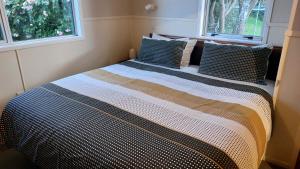 a large bed in a room with two windows at Happy Home in Taupo