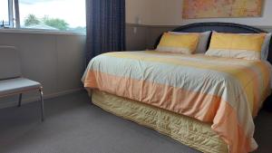 1 dormitorio con 1 cama, 1 silla y 1 ventana en Happy Home with 8 bedrooms en Taupo